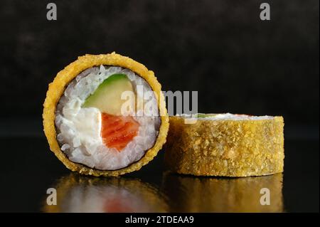 Frittierte japanische Sushi-Rollen auf dunklem Hintergrund mit Reflektor Stockfoto