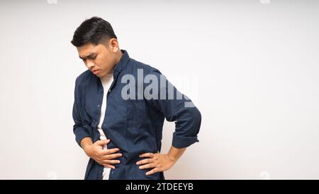 Junger asiatischer Mann mit schmerzhaften Magenschmerzen auf weißem Hintergrund Stockfoto