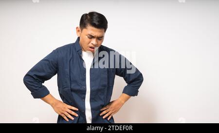 Junger asiatischer Mann mit schmerzhaften Magenschmerzen auf weißem Hintergrund Stockfoto