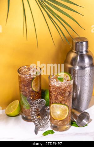 Cuba Libre oder Long Island Sommercocktail, Eiscola mit Limette und Minze. Iced Sweet Long Alkohol Drink mit zerstoßenem Eis und Barutensilien auf High Color Stockfoto