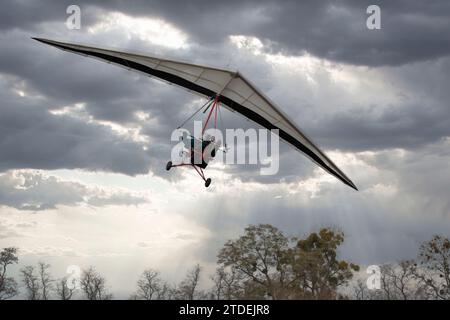 Motorisierter Drachenflieger-Trike-Flügel im Flug mit bewölktem Himmel im Hintergrund Stockfoto