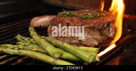 Kochen eines Rib-Eye-Steaks auf einem Grill, Grill oder grill. Ein großes Rippauge mit Knochen, das von einem Grill mit Flamme oder Aufflammung wegfliesst. Rindfleischkonzept Stockfoto