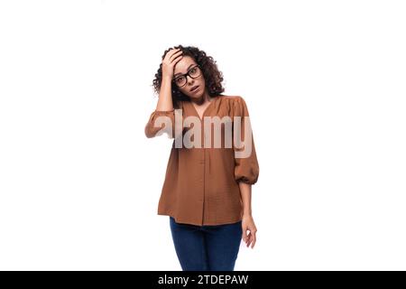 Junge lockige Brünette Geschäftsfrau in braunem Hemd und Jeans Stockfoto