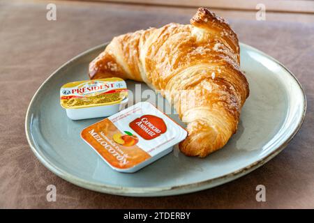 Ein frisch gebackenes Croissant mit Butter und Marmelade zum Frühstück. Stockfoto