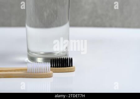 Glaswasser und zwei hölzerne Zahnbürsten Badezimmer auf weißem Hintergrund Stockfoto