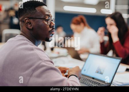 Kollegen in einem Unternehmensbüro arbeiten gemeinsam an Datenanalysen und Marktforschungen mithilfe von Laptops, um Teamarbeit und Zusammenarbeit zu fördern. Stockfoto