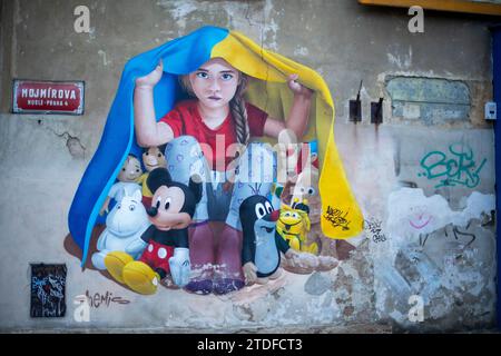 Ein Wandbild eines jungen Mädchens, das unter ukrainischer Flagge in Prag Zuflucht sucht. Wandgemälde Street Art von Chemis Stockfoto