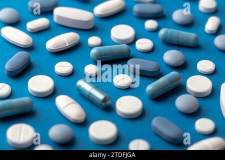 Blaue und weiße Pillen und Tabletten vor blauem Hintergrund Stockfoto