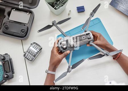 Großansicht der männlichen Hände, die demontierte Drohne mit Werkzeugen am Arbeitsplatz in der technischen Werkstatt halten, Kopierraum Stockfoto