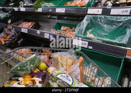 London, Großbritannien. Dezember 2023. Ein Einkaufswagen mit Weihnachtsessen in einem Sainsbury's Supermarkt in Balham. Auf den Regalen hinter dem Wagen befinden sich Karotten und Pastinaken. Quelle: Anna Watson/Alamy Live News Stockfoto