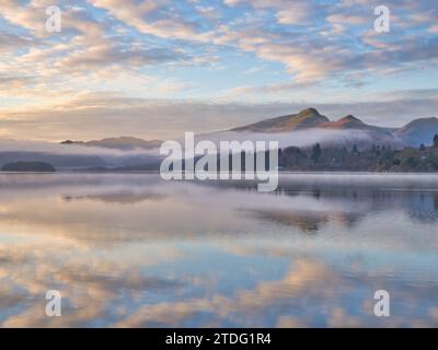 Niedrige Wolken und Nebel hängen an einem frühen Wintermorgen über dem See und den Hängen von Derwentwater. Stockfoto