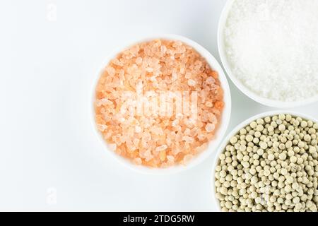 Rosafarbenes Salz, weißer Pfeffer und weißes Salz auf weißem Hintergrund. Ansicht von oben. Stockfoto
