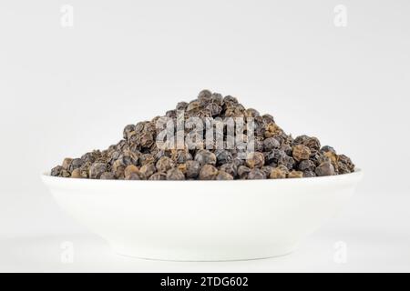 Schwarze Pfeffer oder schwarzer Pfeffer in der weißen Schüssel isoliert auf weißem Hintergrund. Stockfoto