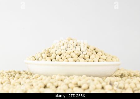 Weißer Pfeffer in einer weißen Schüssel auf einem Stapel weißer Paprika, isoliert auf weißem Hintergrund. Aufnahmen auf Augenhöhe Stockfoto