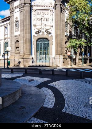 Die Bank of Portugal in Funchal, Madeira, Portugal, zeigt ein für Funchal typisches Stück Kopfsteinpflaster. Stockfoto