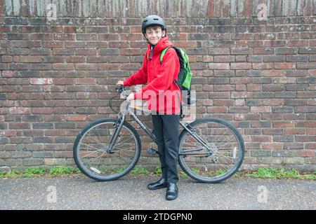 Ein Junge mit dem Fahrrad, bereit, in Uniform zur Schule zu reisen Stockfoto