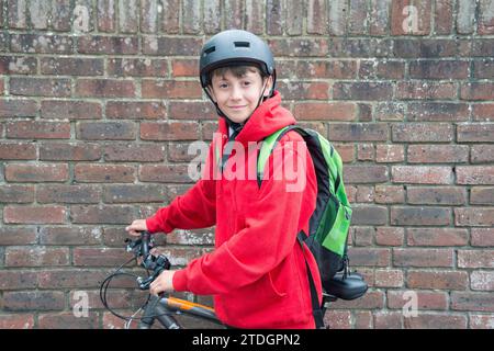 Ein Junge mit dem Fahrrad, bereit, in Uniform zur Schule zu reisen Stockfoto