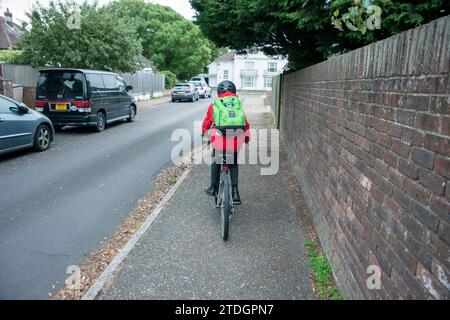 Ein Junge mit dem Fahrrad, bereit, in Uniform zur Schule zu reisen Stockfoto