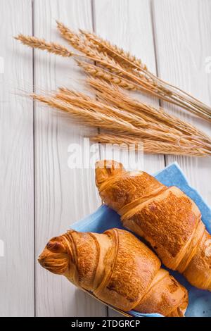 Croissants und Weizenohren auf weißen Holzbrettern Stockfoto