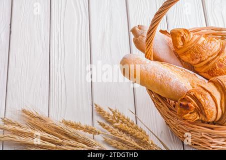 Croissants und Baguettes im Copyspace-Bild in Korbmahren auf weißen Holzbrettern Stockfoto