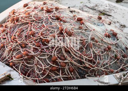 Eine Reihe von Fischernetzen, die sich nach einem Angelausflug auf einem Fischerboot auftürmen. Netze, die durch farbige Seile mit Schwimmern verbunden sind. Stockfoto