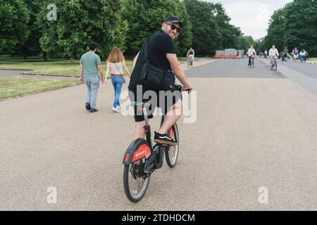 Ein Mann fährt mit einem Leihfahrrad/Verleih-Santander eBike in London durch einen Park Stockfoto