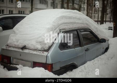 Das Auto steht im Winter auf dem Parkplatz. Das Auto steht im Schnee. Winterparkplätze in der Stadt. Viel Schnee auf der Straße und auf den Transportmitteln. Stockfoto