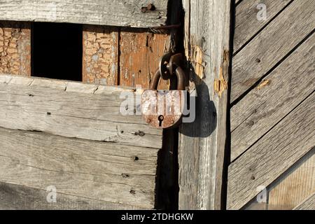 Altes Schloss an der Tür. Rostiges Schloss in der Scheune. Das alte Gebäude im Detail. Aus Dielen. Stockfoto