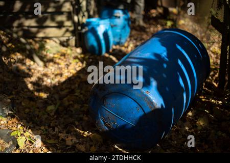 Blaues Fass im Garten. Wasserkanister. Großer Tank liegt auf dem Boden. Gartenwerkzeuge. Stockfoto