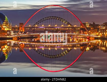 Ein Blick in der Abenddämmerung auf die Tyne-Brücken, die sich im Fluss Tyne spiegeln und vom Ufer newcastle aus auf die Tyne-Brücke blicken Stockfoto