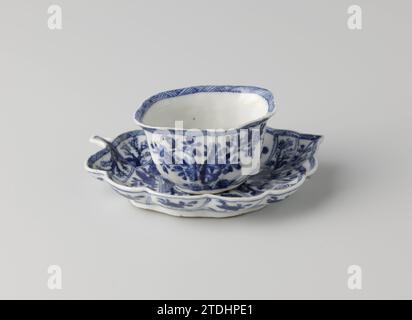 Tasse mit Untertasse in Form eines Blattes, anonym, ca. 1750 - ca. 1774 Porzellankopf und Untertasse, die Schale in Form eines Blattes, in Unterlazblau bemalt. Der Kopf mit modellierten Adern auf der Außenseite und mit einem blühenden Blumenzweig viermal bemalt; Ein Blumenzweig auf der Unterseite; der Rand innen und außen mit einem dekorativen Band mit Schatten. Das Gericht wird durch die „Adern“ des Blattes geteilt, das mit verschiedenen blühenden Pflanzen auf einem Felsen gefüllt ist. Auf der Unterseite des Gerichts mit einem Lotus gekennzeichnet. Blau Weiß. Porzellan. Glasur. Kobalt-(Mineral-)Malerei / Glasur Porzellanheiz Stockfoto