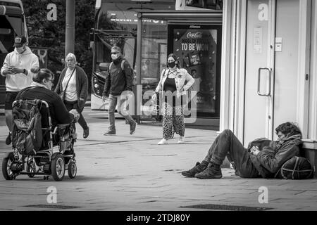 Schwarzweißfoto - Menschen, die an Einem Obdachlosen vorbeigehen, der in der Castle Street, Edinburgh, Schottland, Großbritannien, schläft Stockfoto