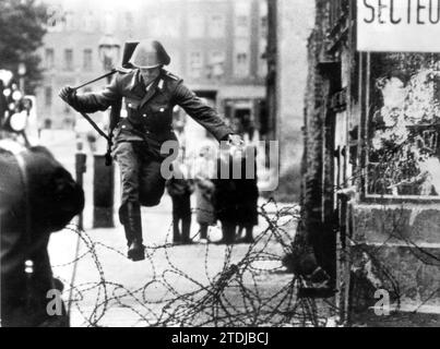 Am 13. August 1961 begann die DDR mit dem Bau von Stacheldrahtzäunen und einer Mauer über Berlin. Zwei Tage später sprang ein Agent der Volkspolizei mit all seiner Ausrüstung über die Stacheldrahthürden in Richtung Westteil Berlins. Quelle: Album/Archivo ABC Stockfoto
