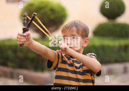 Kleiner Junge, der mit Schleuder im Park spielt Stockfoto