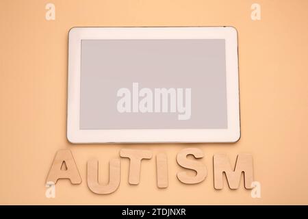 Wort Autismus aus hölzernen Buchstaben und Tafel auf beigefarbenem Hintergrund, flach gelegen Stockfoto