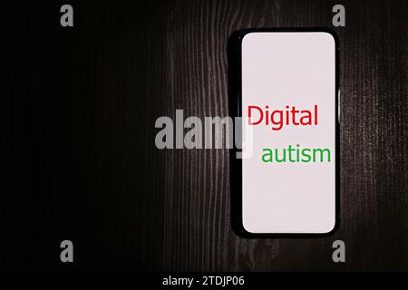 Smartphone mit Phrase Digital Autism auf Holztisch, Draufsicht und Platz für Text. Suchtverhalten Stockfoto