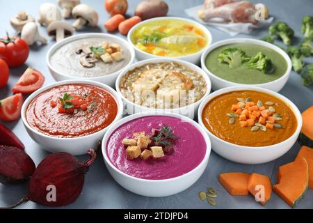 Leckere Brühe, verschiedene Cremesuppen in Schüsseln und Zutaten auf dem Tisch, Nahaufnahme Stockfoto