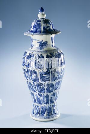 Balusterüberzogene Vase mit Landschaften in Tafeln, anonym, um 1700 Balusförmige Deckelvase aus Porzellan, in Unterlazblau bemalt. Der Bauch ist in fünf Reihen von Lotusblattförmigen Kartuschen mit Landschaften unterteilt. Eine durchgehende Landschaft am Hals. Der glockenförmige Deckel ist in sechs Fächer mit Landschaften unterteilt. Über dem Fuß, an der Schulter, dem Rand und dem Lidrand ein Zickzackband. Ein paar Späne in der Kante des Deckels. Die Deckelvase ist Teil eines Schranksets. Blau Weiß. Porzellan. Glasur. Kobalt-(Mineral-)Bemalung / Verglasung Balusförmige Deckelvase aus Stockfoto