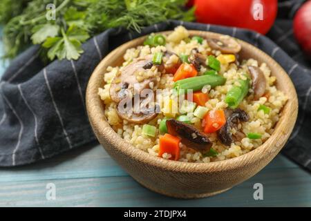 Köstlicher Bulgur mit Gemüse und Pilzen auf hellblauem Holztisch, Nahaufnahme Stockfoto