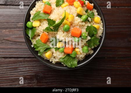 Leckerer Quinoa-Brei mit Gemüse in Schüssel auf Holztisch, Blick von oben Stockfoto