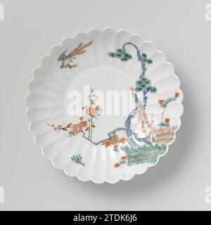 Saucer-dish with the 'three friends' near brushwood fences and two hoo-birds, anonymous, c. 1670 - c. 1690 Scale of porcelain with a ribbed wall and a lobed edge, painted on the glaze in blue, red, green, yellow, black and gold. On the front the 'Three Friends of Winter' (Bamboo, Prunus, Pijnboom) behind two hedges. One Hoo-Vogel on a branch, the other flying. Arita, Kakiemon. Japan porcelain. glaze. gold (metal) painting / gilding / gilding Scale of porcelain with a ribbed wall and a lobed edge, painted on the glaze in blue, red, green, yellow, black and gold. On the front the 'Three Friends Stockfoto