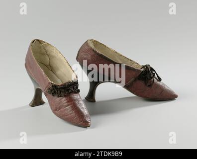 Paar Damenschuhe mit Rüschen, ca. 1785 - ca. 1795 Schuh aus dunkelrotem Leder. Modell: Spitse Nose, ein Deckblatt und zwei Seitenbleche. Die Nähte, die die Klingen zusammenhalten, waren ursprünglich mit schwarzen Seiten bedeckt. Die Vorderseite der Ferse verläuft gerade nach unten in einem abgerundeten Winkel zur Gelbfärbung. Die Seite und Rückseite der schmalen Ferse sind mit schwarzem Leder versehen. Entlang der Fersenkante sind weiße Nähte angebracht. Lernen Sie hinter der Ledersohle. Seitenlaken und Deckblätter sind mit beigefarbenem Leinen ausgekleidet. An der Ferse ist ein dreieckiges Stück elfenbeinfarbenes weißes Leder angebracht. Die Eins Stockfoto