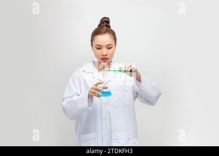 Ein asiatischer Wissenschaftler, der eine flüssige Lösung in einem Labor hält. Stockfoto