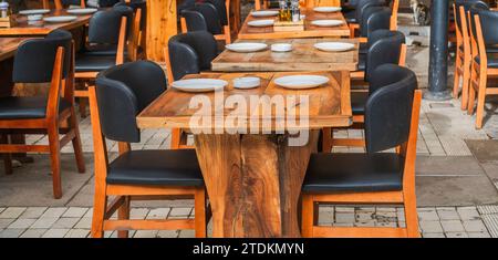 Restaurant im Freien. Altmodische Café-Terrasse. Holztisch. Café im Freien mit Holztischen. Natürliche Tische im Straßencafé an einem sonnigen Sommertag Stockfoto