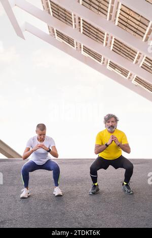 Senior-Mann, der ein Hocktraining mit seinem Trainer macht Stockfoto