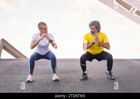 Senior-Mann, der ein Hocktraining mit seinem Trainer macht Stockfoto