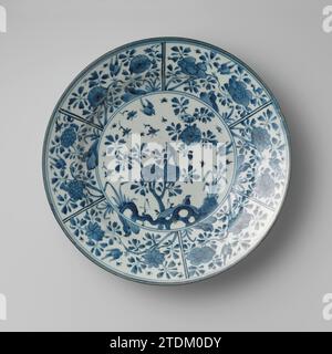 Schüssel mit Vögeln und Insekten in der Nähe von blühenden Pflanzen und einem Felsen, anonym, ca. 1650 - ca. 1699 Untertasse aus Porzellan, in Unterglasurblau bemalt. Auf der Ebene eine blühende Pflanze (camelia) in einem Felsen. Fliegende Vögel und Insekten um sie herum. Die Wand und der Rand sind in sechs Bereiche unterteilt, in denen ein Vogel auf einem Felsen in der Nähe einer blühenden Pflanze, ein fliegende Vogel und Insekten stehen. Die Außenwand mit vier Blumenzweigen. Vier Pronen auf dem Boden. Blau Weiß. Japanisches Porzellan. Glasur. Kobalt-(Mineral-)Malerei / Glasur Untertasse aus Porzellan, in Unterglasurblau lackiert. Auf der Ebene eine blühende Pflanze (camelia) in einem Felsen. Fliegen Stockfoto