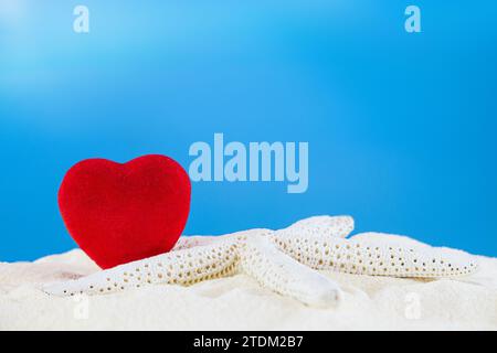 Rotes Herz mit weißem Stern auf dem Sand des Strandes. Valentinstag, Liebe, Urlaub. Kopierbereich Stockfoto