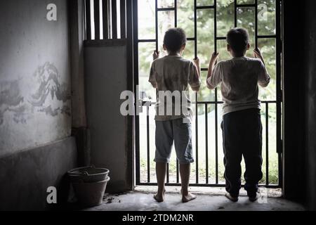 Kinder, die in einem Raum mit einem Stahlkäfig gefangen waren. Das Konzept der Bekämpfung von Gewalt gegen Kinder und Menschenhandel. Stockfoto