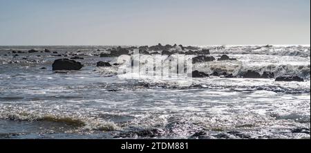 Blaues Meer und stürmende Felsen. Wellen sprühen über Felsen. Felsige Küste. Stockfoto